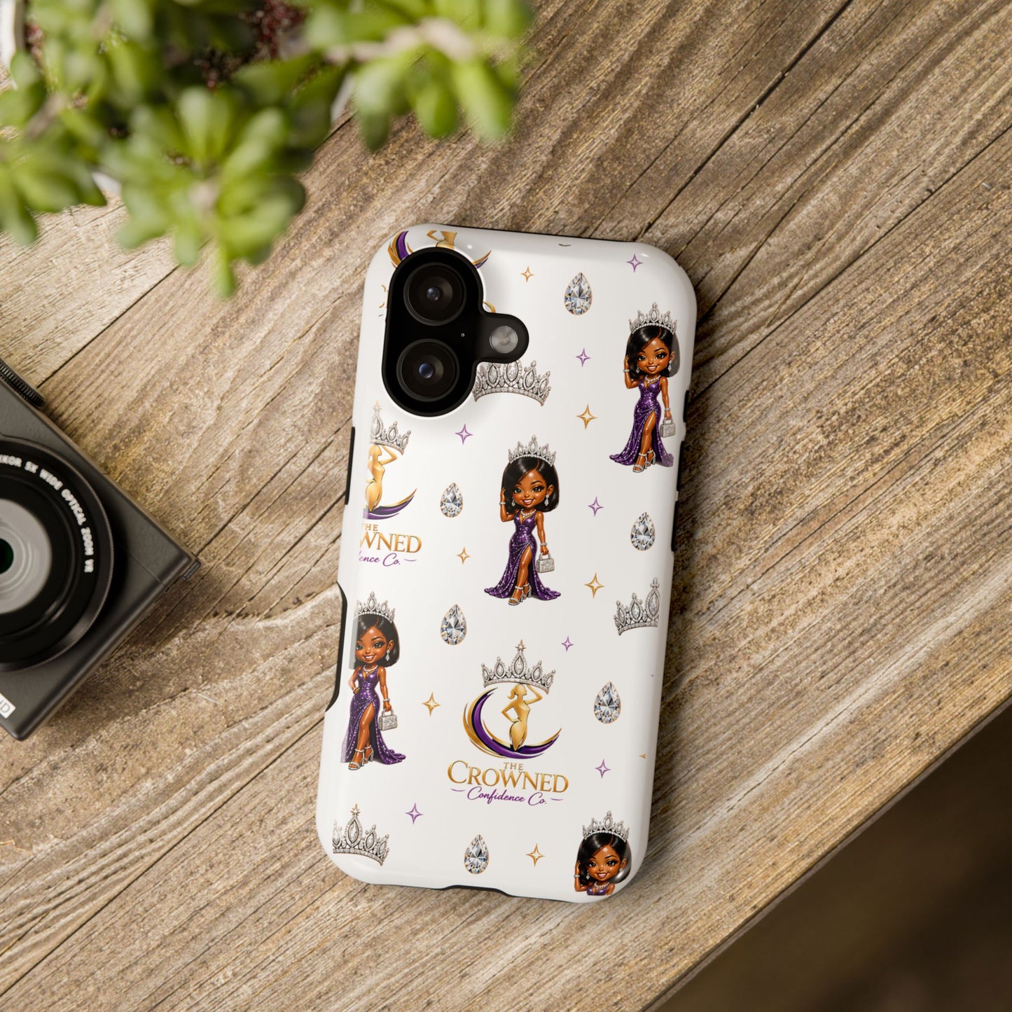 Phone case with 'Crowned' branding on a wooden surface
