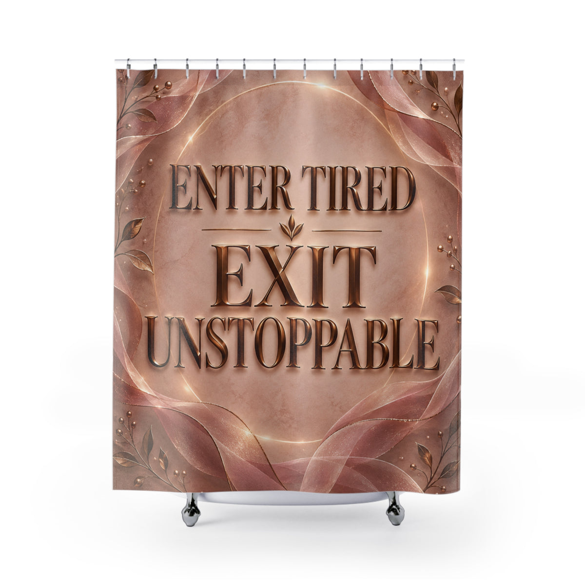 A novelty shower curtain featuring the text 'ENTER TIRED EXIT UNSTOPPABLE' in raised metallic lettering over a warm copper and rose-gold abstract background with decorative leaf motifs. The curtain is shown hanging from silver hooks above a white tub edge against a light gray studio background.