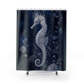 A shower curtain featuring a detailed white seahorse and sea plant design on a dark navy blue background, shown hanging from silver hooks with a white tub edge visible at the bottom.