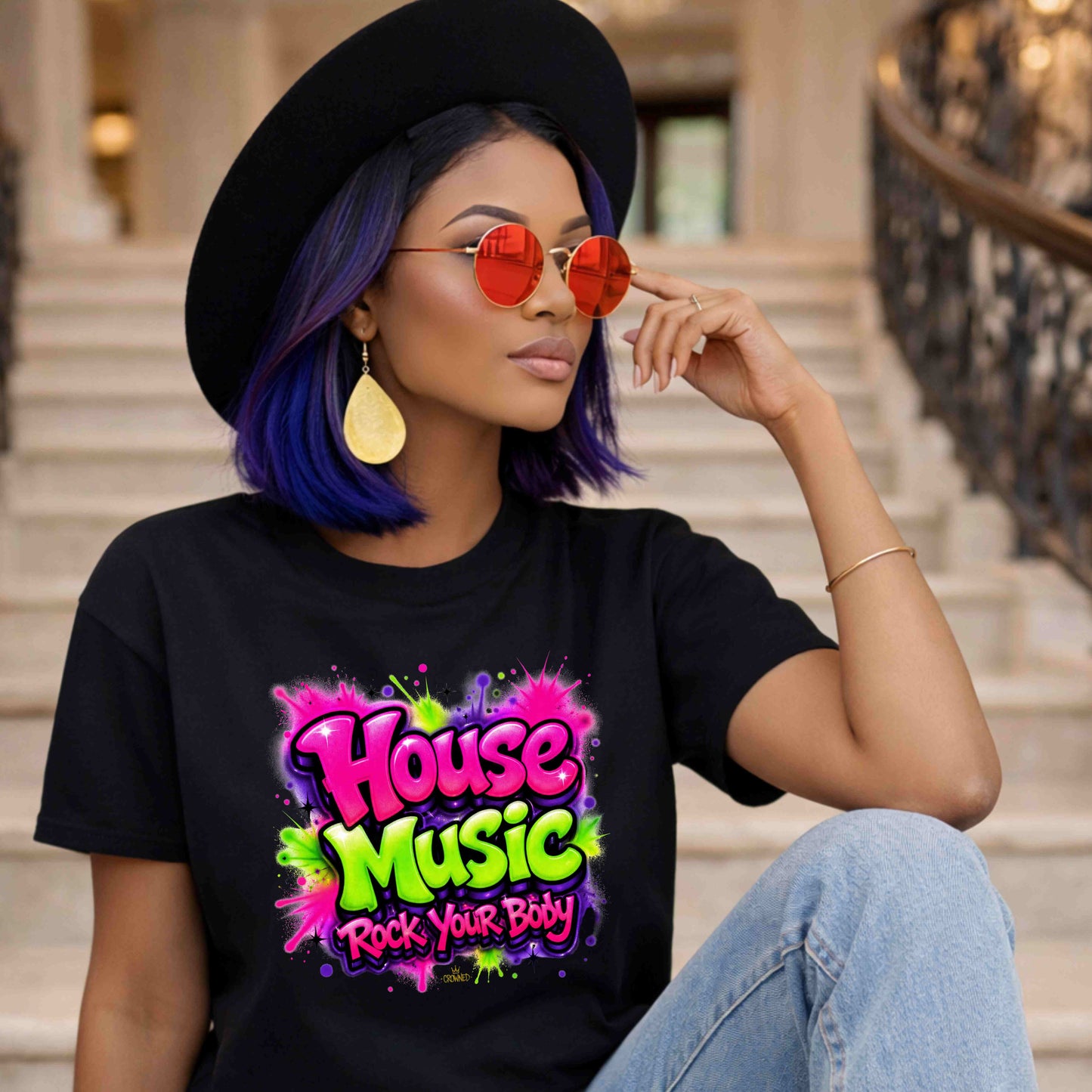 Woman wearing a black t-shirt with 'House Music Rock Your Body' design, sitting on stairs.