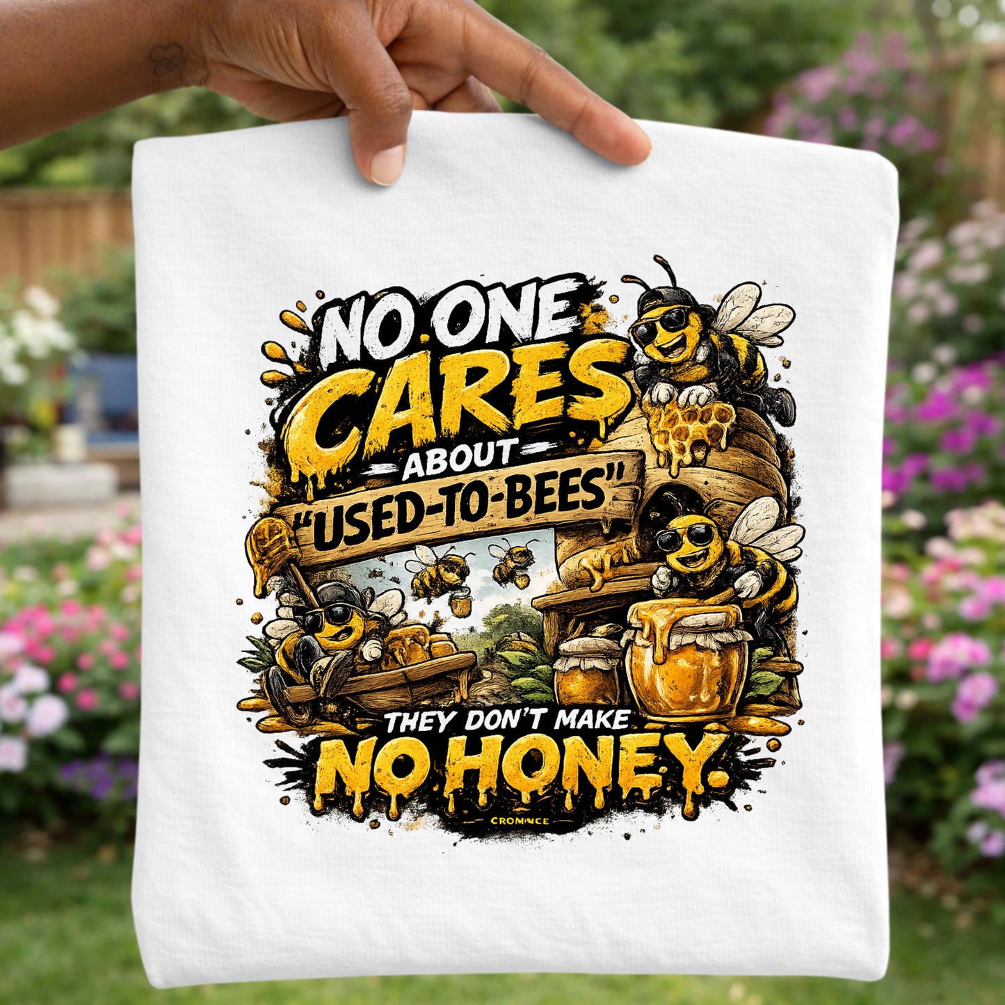 T-shirt with bee-themed design and text held in front of a garden background