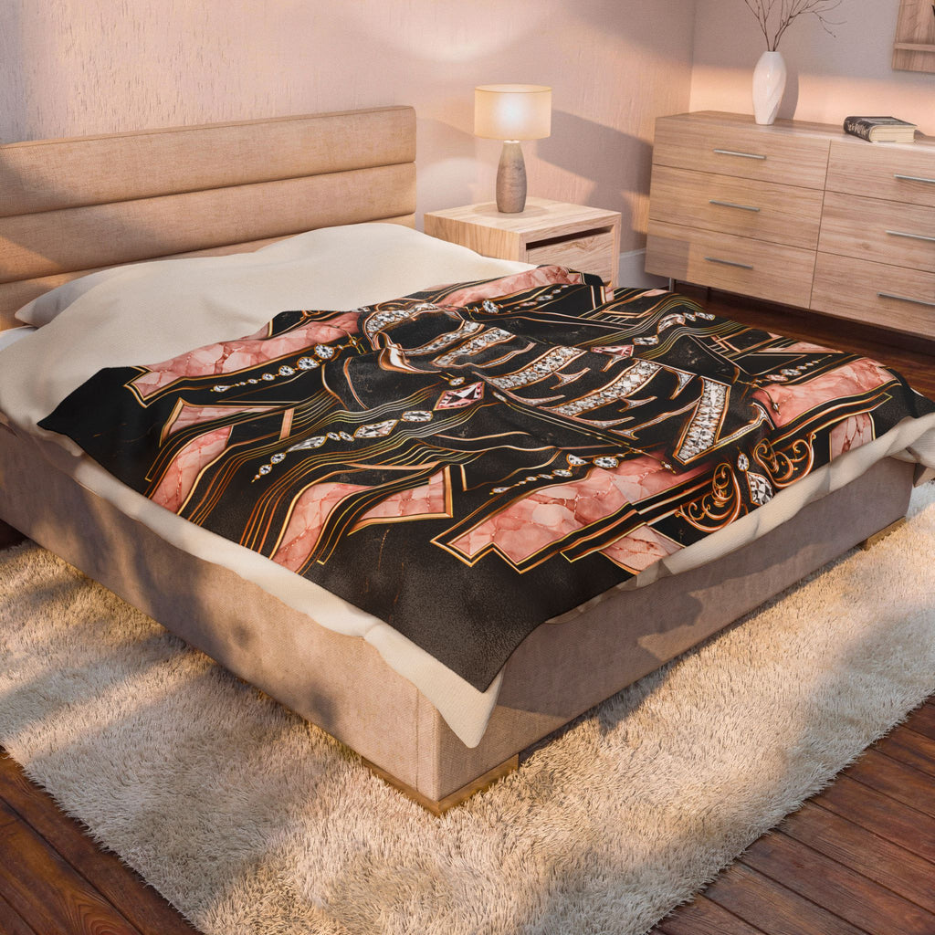 A bed in a styled bedroom setting, covered with a black throw blanket featuring a pink and gold abstract pattern.