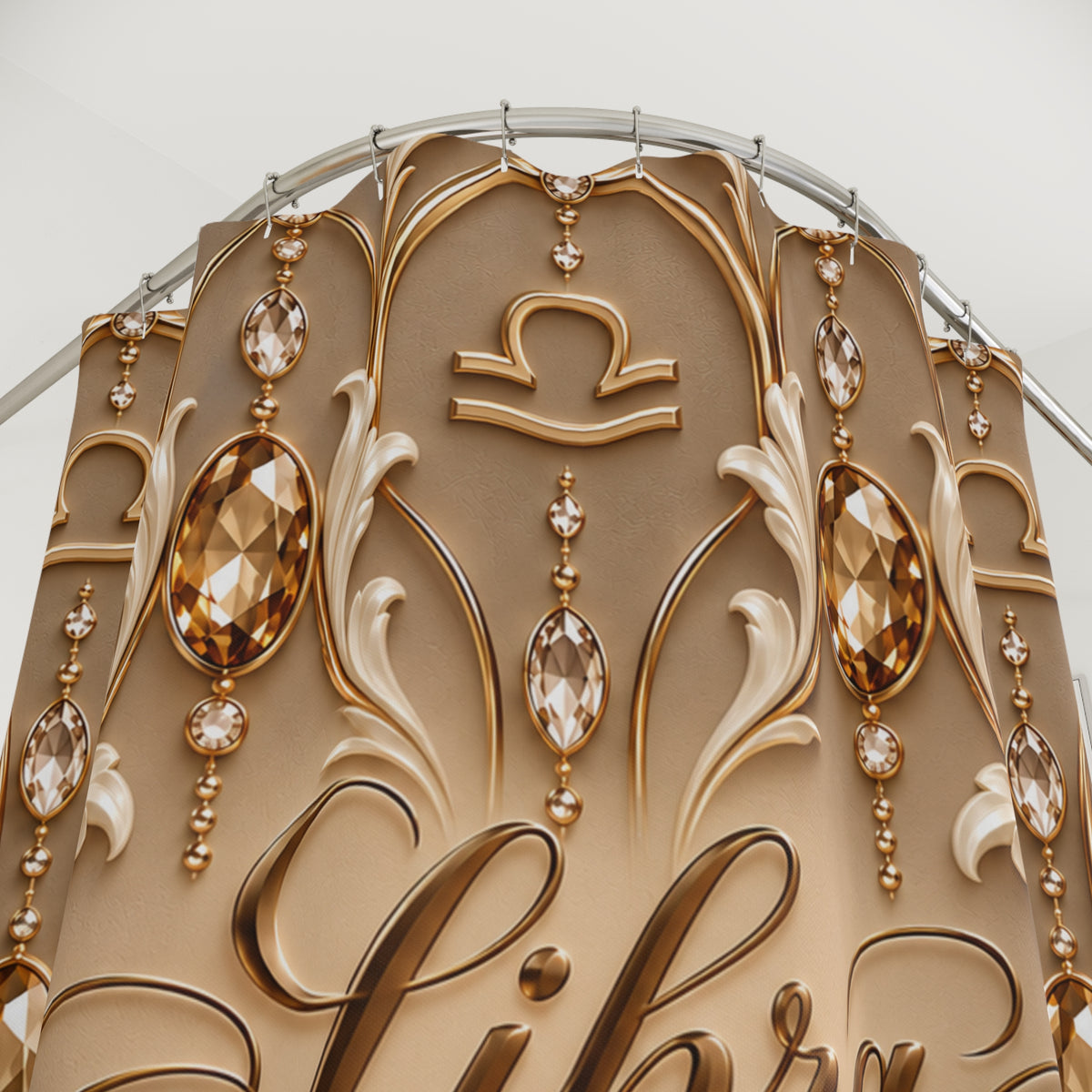 Close-up of an ornate decorative shower curtain with gold and beige scrollwork, faceted crystal-like drops, and a zodiac symbol near the top, photographed against a light neutral background.