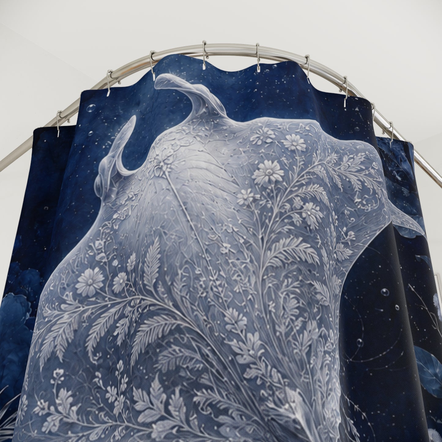 A dark blue shower curtain featuring a large white floral and leafy botanical pattern, hanging from a curved metal rod against a plain light background.
