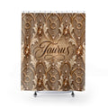 A shower curtain featuring an ornate gold and beige damask-style pattern with hanging bead strands and the word 'Taurus' in script at the center, shown on a white background with small silver hooks and feet visible.