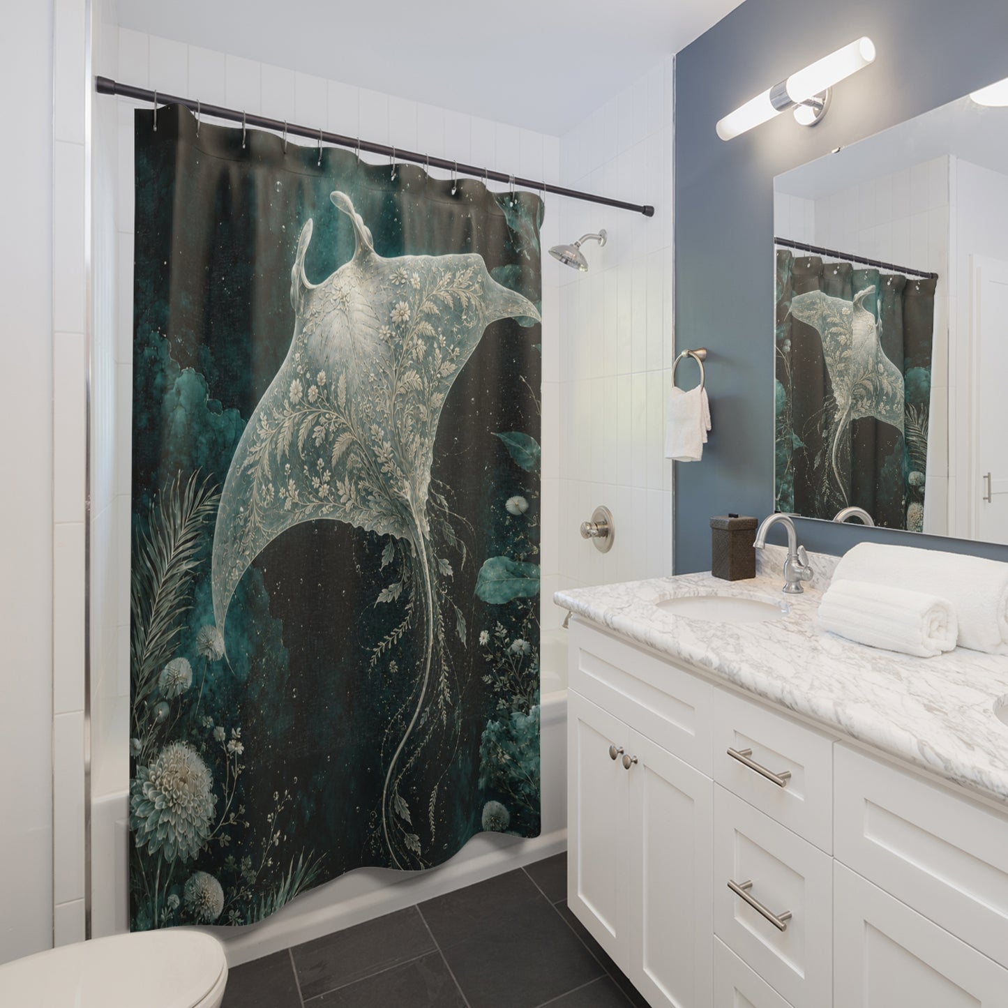 A bathroom scene showing a shower curtain with a large manta ray underwater print in dark teal, black, and white. The bathroom includes a white vanity with a marble countertop, a mirror reflecting the shower curtain, and a bathtub area.