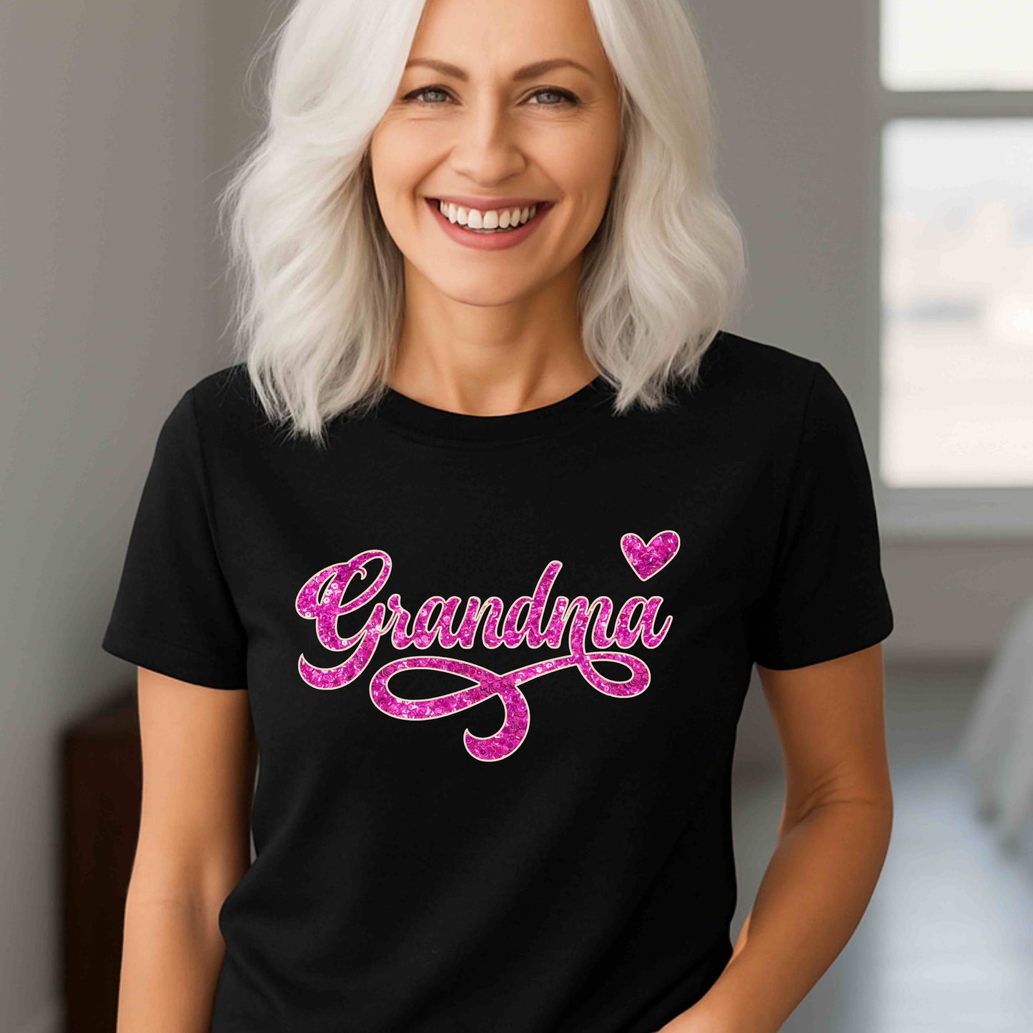 Woman wearing a black t-shirt with pink 'Grandma' text and heart design.