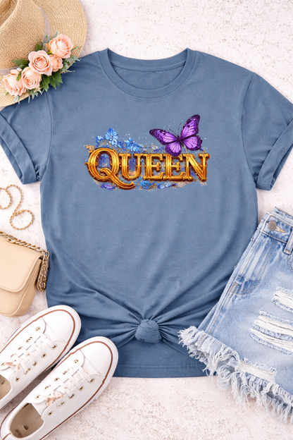 Blue t-shirt with 'QUEEN' text and butterfly graphic, surrounded by accessories on a light surface.
