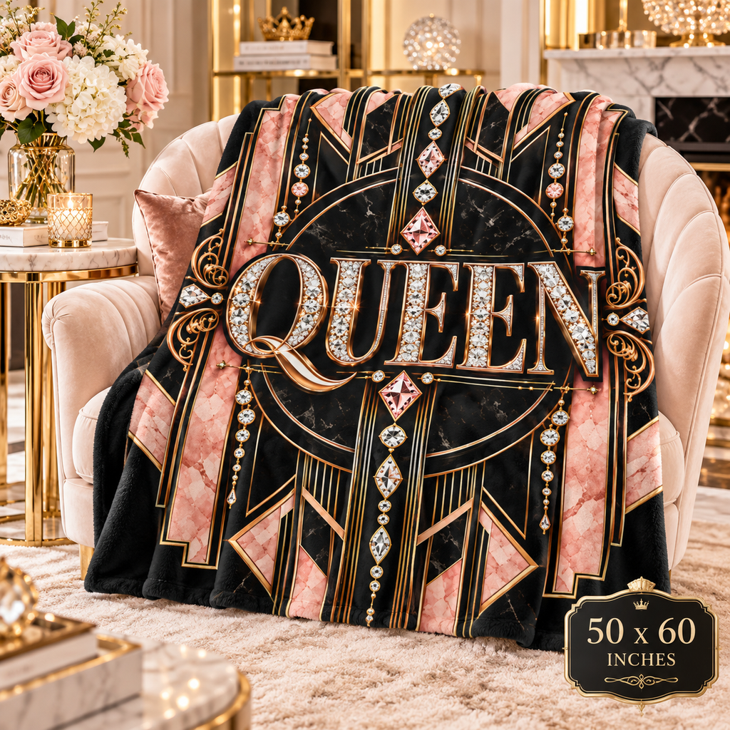 An Art Deco style throw blanket draped over a pink armchair in a luxurious room setting. The blanket features a black and pink marble background with gold geometric lines, rhinestone details, and the word 'QUEEN' in large letters.